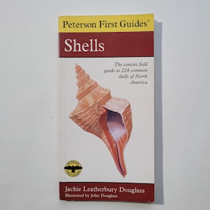 May include: A Peterson First Guides book cover featuring a colorful illustration of a seashell with the title "Shells" and the text "The concise field guide to 224 common shells of North America".