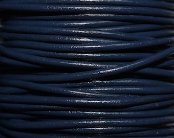 May include: Close-up of a spool of dark blue leather cord. The cord is tightly wound and has a smooth, polished finish.