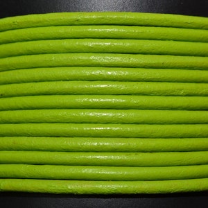 May include: Close-up of a spool of bright green leather cord. The cord is smooth and has a slight sheen.