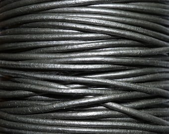 May include: Close-up of a spool of black leather cord. The cord is tightly wound and has a smooth, polished finish.