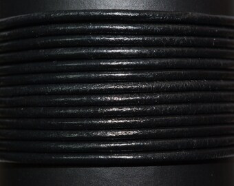 May include: Close-up of a spool of black leather cord. The cord is wound tightly around the spool, creating a textured pattern.