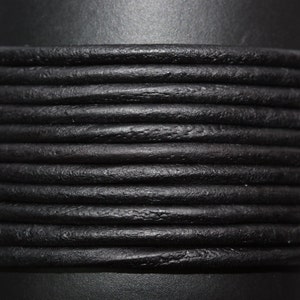 May include: Close-up of black leather cord, showing the texture and detail of the material.