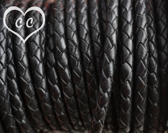 May include: Close-up of black braided leather cord. The cord is tightly wound and has a smooth, textured surface.