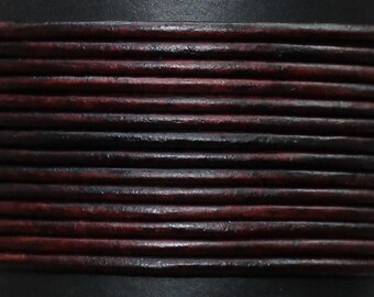 May include: Close-up of a dark brown leather cord with a reddish-brown hue. The cord is made of multiple strands of leather that are woven together to create a textured look.