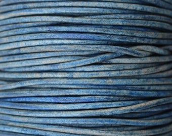 May include: A close-up of a spool of blue leather cord. The cord is tightly wound and has a slightly distressed look.