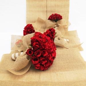 May include: Three bouquets of red roses wrapped in hessian fabric. The bouquets are arranged on a hessian background.