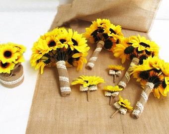 May include: A set of six sunflower bouquets with burlap and lace accents. The bouquets are arranged on a hessian surface. The largest bouquet is a bridal bouquet, and the smaller bouquets are bridesmaid bouquets, buttonholes, and corsages.