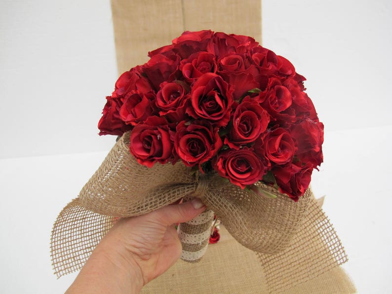 May include: A bouquet of red roses wrapped in hessian fabric with a hessian bow.