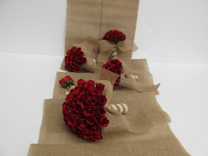 May include: Four bouquets of red roses wrapped in hessian fabric. The bouquets are arranged on a hessian surface.
