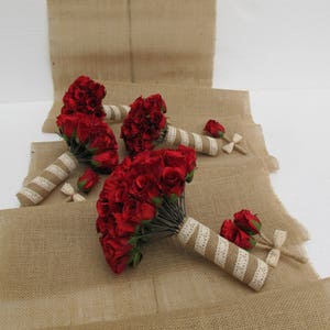 May include: Four red rose bouquets tied with white ribbon and hessian. The bouquets are arranged on a hessian surface.