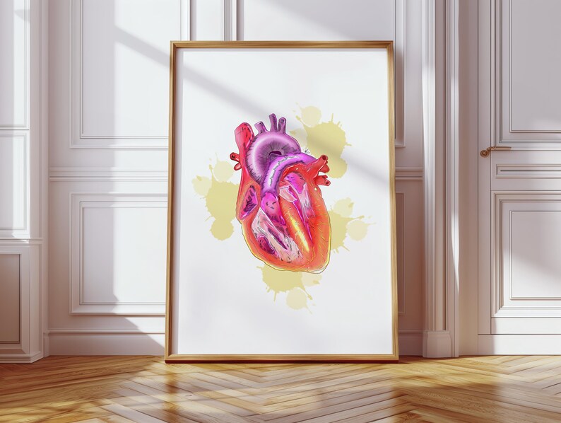May include: A framed print featuring a detailed, colorful illustration of a human heart. The artwork showcases the heart's anatomy with shades of red, pink, and purple, set against a white background with yellow paint splatters. The frame is a warm, natural wood tone.