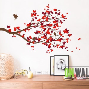 May include: A wall decal featuring a brown tree branch with red leaves and small birds. The decal is designed to be applied to a wall, creating a decorative nature-themed accent. The design includes falling leaves.