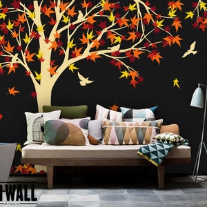 May include: A black wall with a large white tree silhouette with orange and red leaves. The tree is decorated with small white birds. A couch with pillows and a throw blanket is in front of the wall. The text "ON WALL STUDIO" is in the bottom left corner of the image.