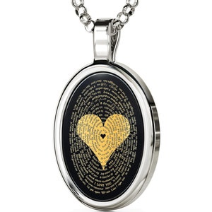 A silver oval pendant necklace with a black background and a gold heart design. The heart is made up of words in different languages that say 'I love you.' The words are arranged in a spiral pattern around the heart.
