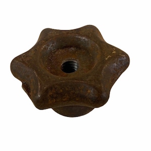 May include: A rusty brown metal star-shaped knob with a threaded hole in the center.