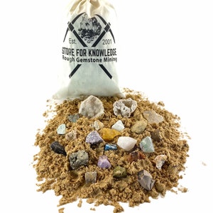 May include: A white canvas bag with the text "Est. 2001 Store for Knowledge Rough Gemstone Mining" printed on it. The bag is filled with a variety of colorful gemstones and crystals, including amethyst, quartz, and citrine.