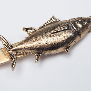 May include: A gold-toned tie clip featuring a detailed, three-dimensional fish design.