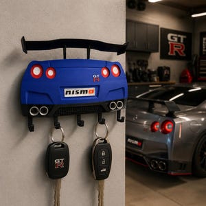May include: A blue car-shaped key holder with a black spoiler and the word "nismo". The key holder has four hooks and two keys hanging from it. The keys have the GT-R logo.