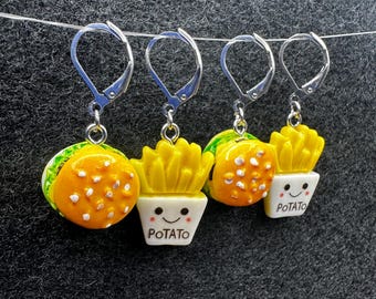 May include: Three pairs of earrings featuring a yellow and white hamburger and french fries. The french fries are in a white container with a smiling face and the text "POTATO".