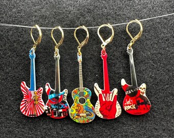May include: Five colorful guitar-shaped earrings with different designs. The earrings are made of metal and have a gold-colored finish. The designs include a red, white, and blue guitar with a skull and crossbones, a black and white guitar with a skull and crossbones, a red guitar with a peace sign, a colorful guitar with a psychedelic design, and a black guitar with a rock and roll design.