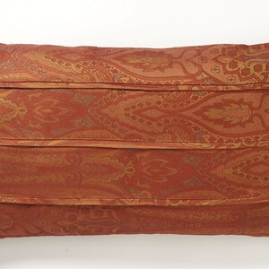 May include: A rectangular pillow with a red and gold paisley pattern. The pillow has four horizontal seams that create a pleated effect.