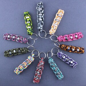 May include: A collection of 11 colorful keychains with different patterns and designs. Each keychain features a series of metal hexagonal beads and a silver key ring.