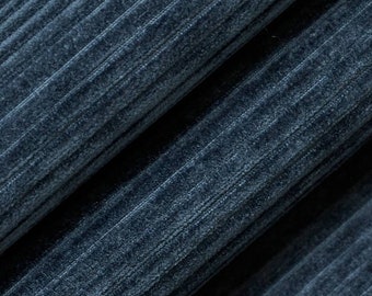May include: Close-up of a textured fabric in a deep blue hue. The fabric has a corduroy-like appearance with vertical ridges and a soft, velvety texture. The folds and shadows create depth and dimension.