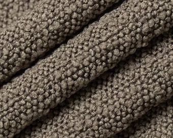 May include: Close-up of a brown textured fabric with a raised, bumpy pattern. The fabric has a soft, fuzzy appearance.