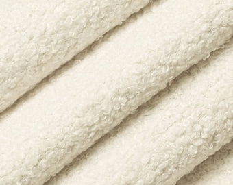 May include: Close-up of a soft, white, fluffy fabric with a textured surface. The fabric is folded in layers, showing the texture and softness.