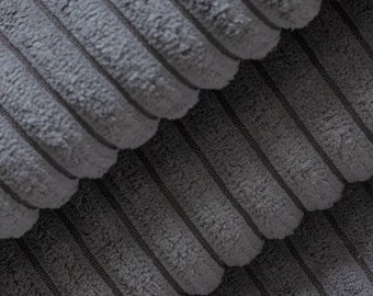 May include: Close-up of a stack of gray corduroy fabric. The fabric has a ribbed texture and a soft, fuzzy surface.