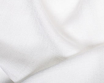 May include: White fabric with a textured surface. The fabric is folded and draped, creating soft folds and wrinkles.