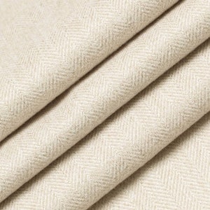 May include: Close-up of a beige herringbone fabric with a subtle texture. The fabric is folded in a way that shows the pattern and weave.