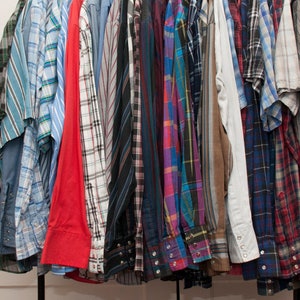 May include: A collection of plaid shirts in various colours, including blue, red, green, and black, hanging on a rack.