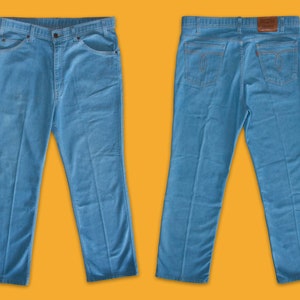 May include: A pair of blue denim jeans with a straight leg fit. The jeans have a classic five-pocket design and a brown leather patch on the back.