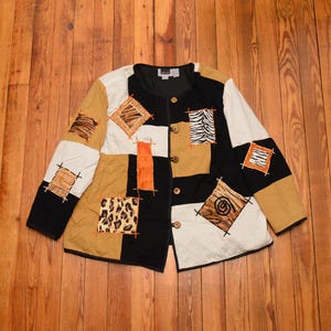 May include: A black, brown, white, and orange patchwork jacket with animal print designs. The jacket has a button closure and a collar.