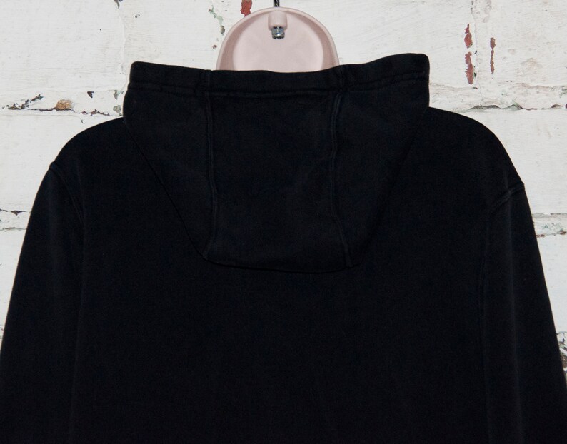 May include: Black hooded sweatshirt with a drawstring hood. The sweatshirt is made of a soft, comfortable fabric.