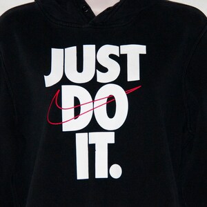 May include: Black hooded sweatshirt with a white "Just Do It" logo and a red Nike swoosh.