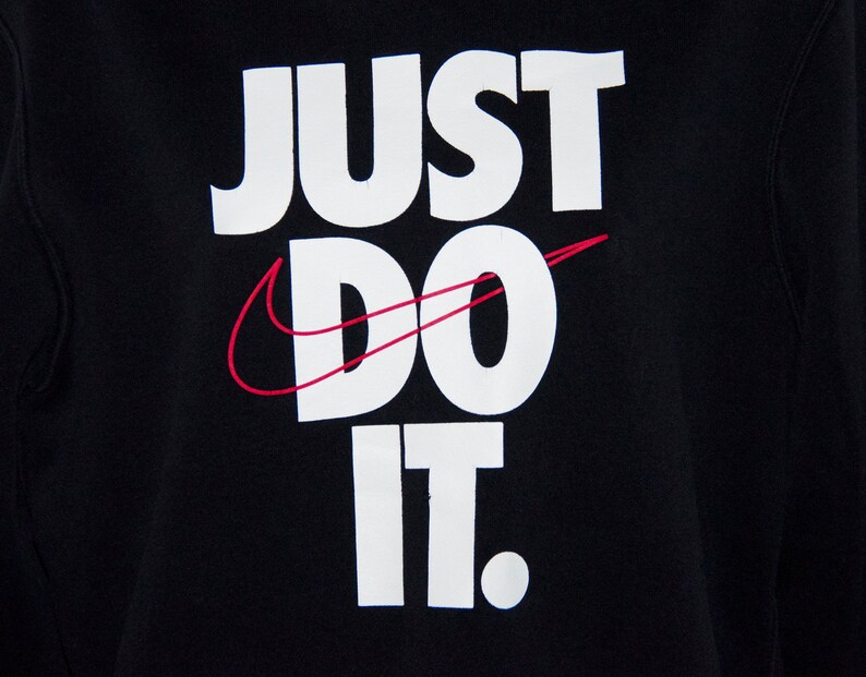 May include: Black sweatshirt with white text that reads "Just Do It." The Nike swoosh logo is in red.