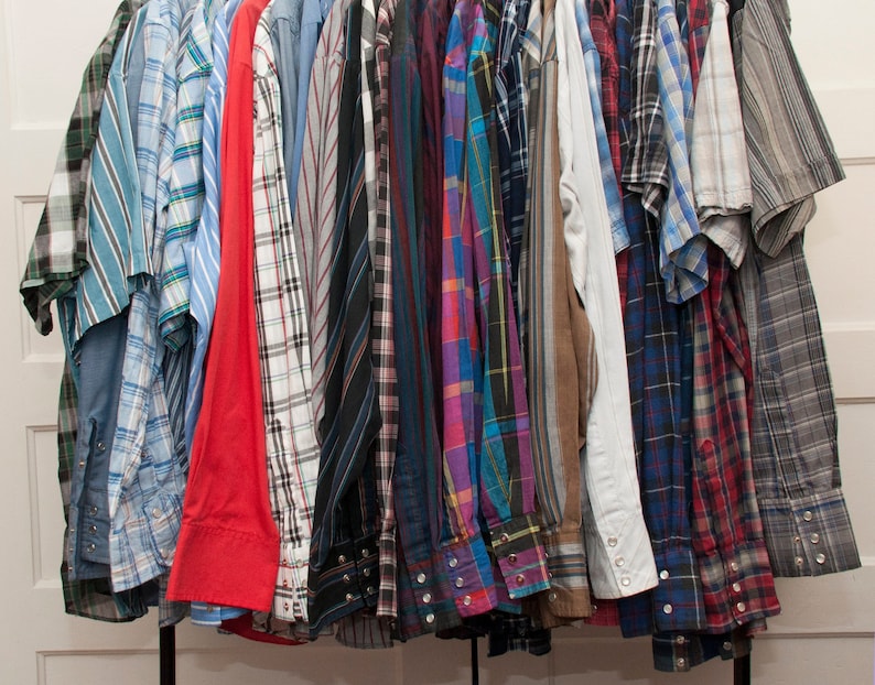 May include: A collection of plaid shirts in various colours, including blue, red, green, and black, hanging on a rack.