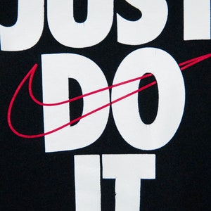 May include: Black t-shirt with white text that reads "Just Do It" and a red Nike swoosh.