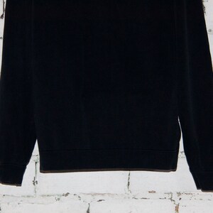 May include: A black long-sleeved sweatshirt with a ribbed crew neck and cuffs.