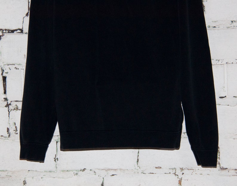 May include: A black long-sleeved sweatshirt with a ribbed crew neck and cuffs.