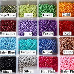 May include: A clear plastic storage container with twenty-four compartments filled with small, round, colored beads. Each section contains a specific color labeled with text including Teal, Sage/Olive, Lime, Green, Gold, Lemon, Navy, Burgundy, Lilac, Purple, Red, Orange, Aqua, Baby Blue, Turquoise, Royal, Taupe, Brown, White, Black, Silver, Hot Pink, Baby Pink, and Rose.