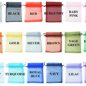 May include: A collection of eighteen rectangular organza drawstring pouches arranged in three rows. Each sheer fabric bag is labeled with its corresponding color: white, black, red, burgundy, baby pink, hot pink, orange, gold, silver, brown, sage green, emerald green, aqua blue, turquoise, royal blue, navy, lilac, and purple.