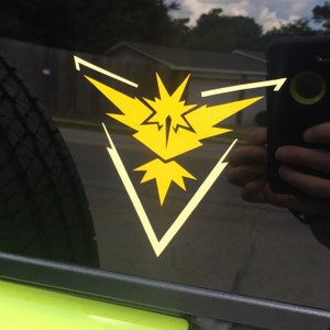 Op de afbeelding: Een gele en witte vinyl sticker van het Pokémon-personage Articuno op een zwarte achtergrond.