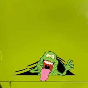 May include: Green cartoon ghost with a big smile and a long pink tongue sticking out. The ghost is peeking out from behind a black and white background.
