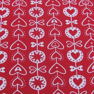 May include: Red fabric with a white repeating pattern of hearts, stars, and stylised flowers. The pattern is a simple, modern design.