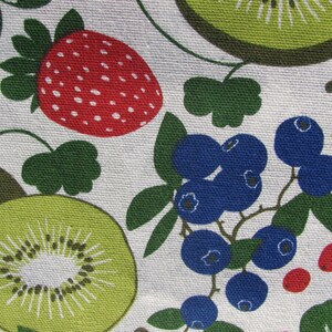 May include: A white fabric with a repeating pattern of green leaves, red strawberries, blue blueberries, and green kiwi fruit.