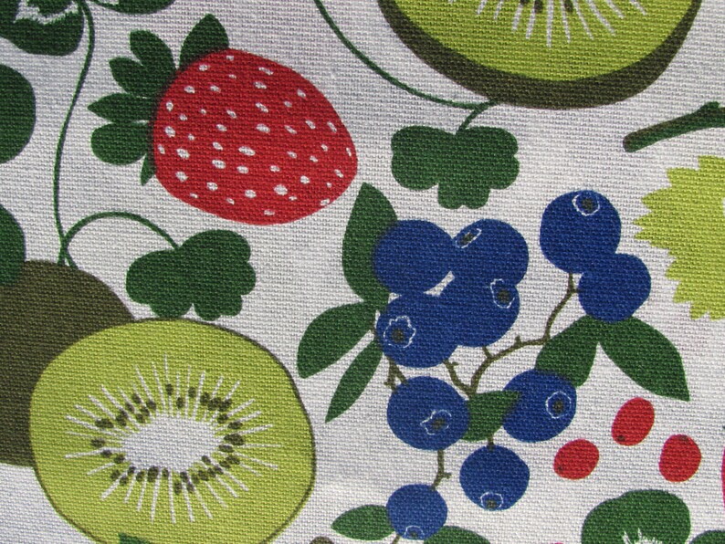 May include: A white fabric with a repeating pattern of green leaves, red strawberries, blue blueberries, and green kiwi fruit.
