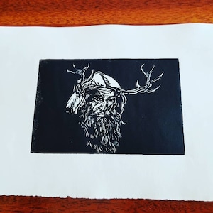 Puede incluir: Grabado en madera en blanco y negro de un hombre barbudo con cuernos de ciervo en la cabeza. El hombre lleva un sombrero y tiene una expresión seria en su rostro.